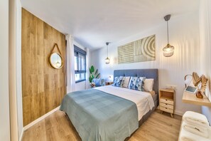 Ein Schlafzimmer mit Holzwand, einem Bett mit blauer und weißer Bettdecke, einem Nachttisch mit Lampe und einem an der Wand befestigten Spiegel.