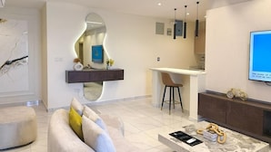 Ein modernes Wohnzimmer mit einer Couch, einem Couchtisch und einer Küchenzeile mit einem Barhocker.