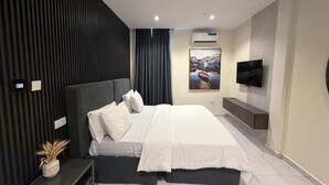 Ein modernes Schlafzimmer mit einem Bett, einem an der Wand montierten Fernseher und einer Klimaanlage.
