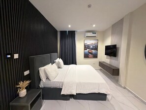 Ein modernes Schlafzimmer mit einem Bett, einem an der Wand montierten Fernseher und einer Klimaanlage.