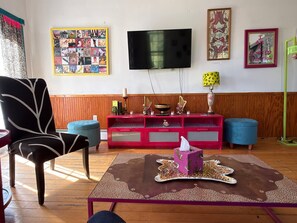 Ein Wohnzimmer mit Fernseher, einer roten Unterhaltungseinheit, einem blauen Sofa, einem Tisch mit Leopardenmuster und einem Sessel.
