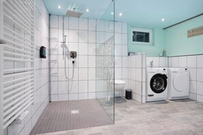 Een moderne badkamer met een douchecabine van glas, een toilet en een wasmachine.