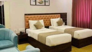 Hotellihuone, jossa on kaksi sänkyä, yöpöytä, tuoli ja seinälle ripustettu taideteos.