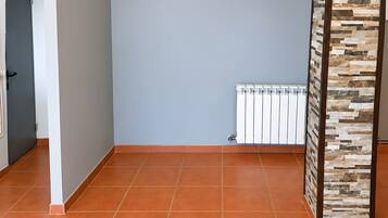 Une pièce dotée d’un sol carrelé, d’un radiateur et d’une porte donnant sur une autre pièce.