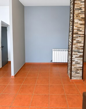A room with a tiled floor, a radiator, and a door leading to another room. - Villa 'Ana Esperanza - El Espinar' with Lake Views, Wi-Fi, and Air Conditioning (El Espinar)