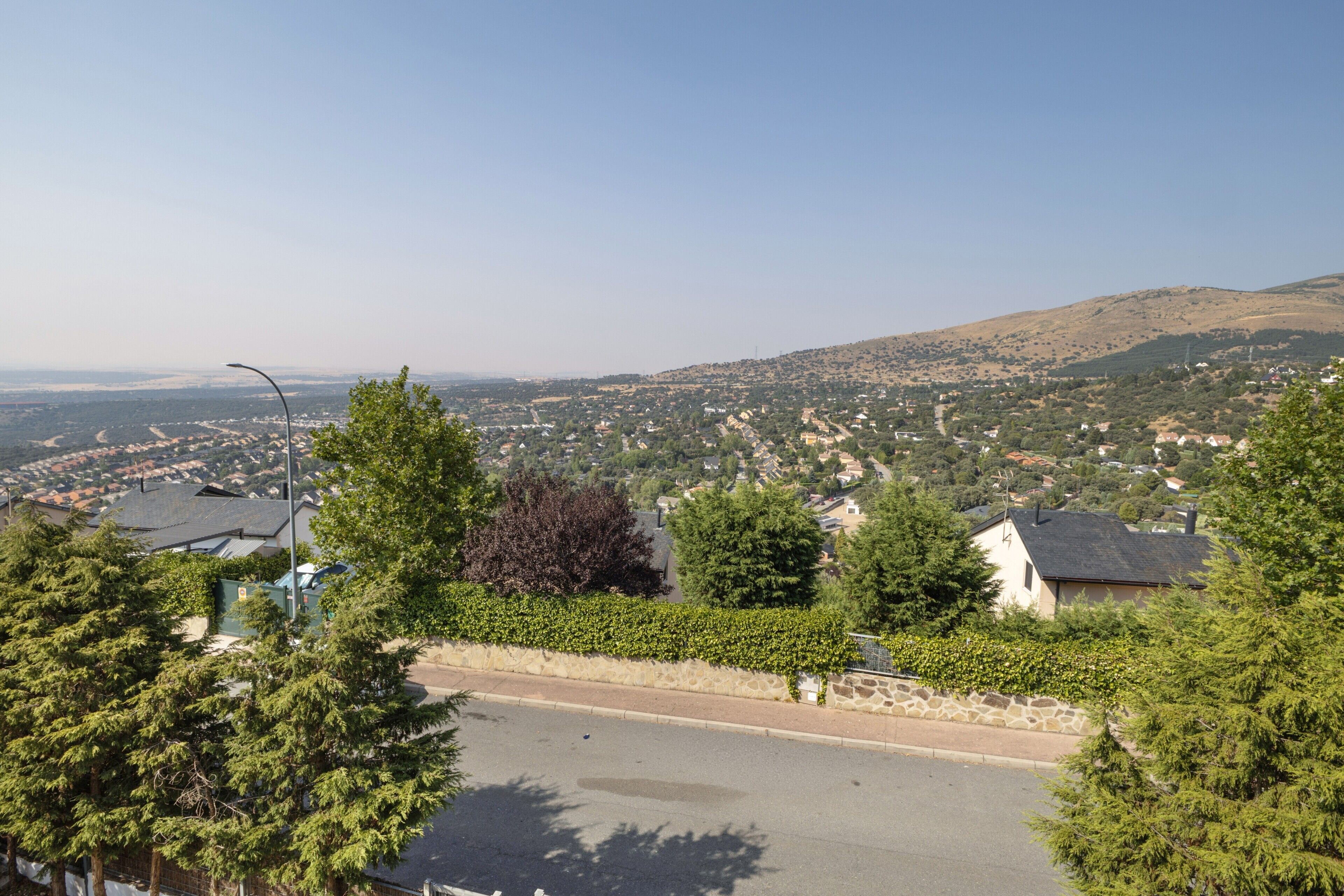 Una zona residencial con casas, una carretera y un paisaje montañoso al fondo.