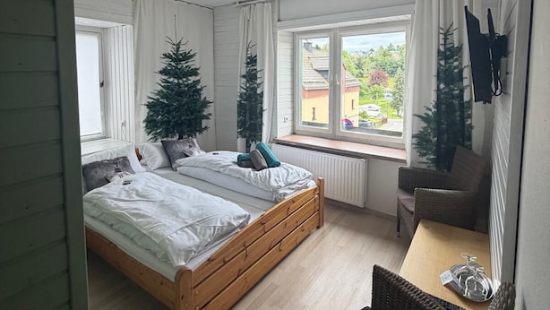 Un dormitorio con una cama de madera, una mesita, una silla y dos árboles de Navidad.