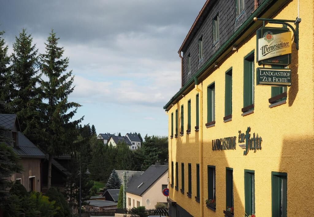 Un edificio amarillo con un letrero que dice 'Wemsegriner' y 'Landgasthof Zur Fichte'.