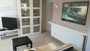 Una sala de estar con televisor, un mueble, un sofá y un cartel en la pared.