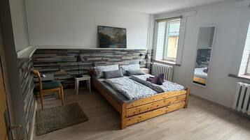 Une chambre à coucher avec un lit en bois, un tableau au mur, une fenêtre et un radiateur.