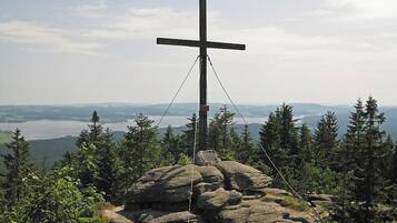 A cross on a rock with a view of a lake and mountains.