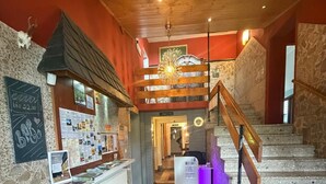 Un vestíbulo de hotel con mostrador de recepción, alfombra roja, una escalera y un candelabro.