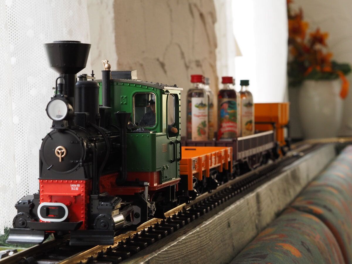 A model train with a green locomotive and orange cars on a track.