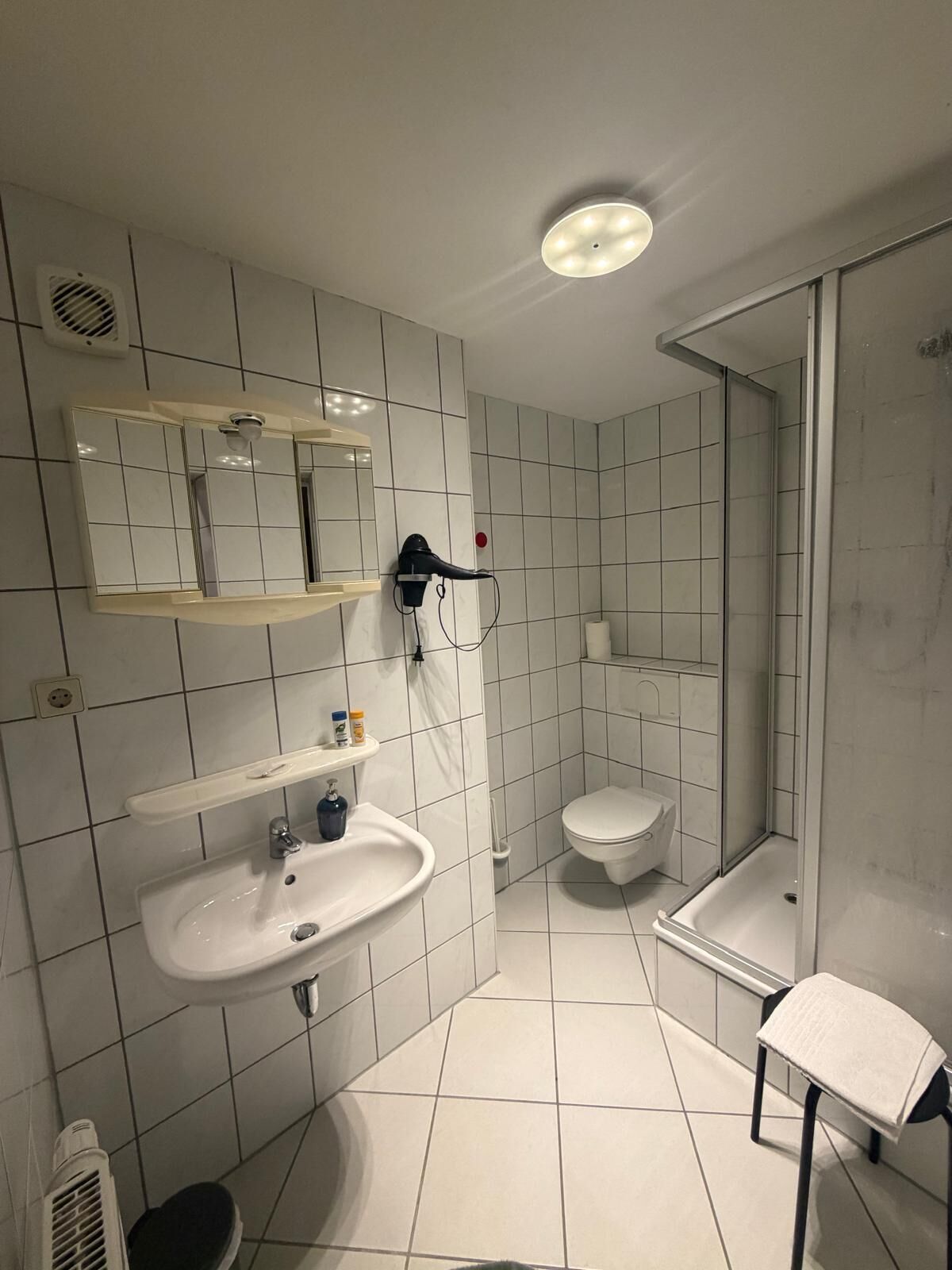 A modern bathroom with a sink, mirror, and shower.