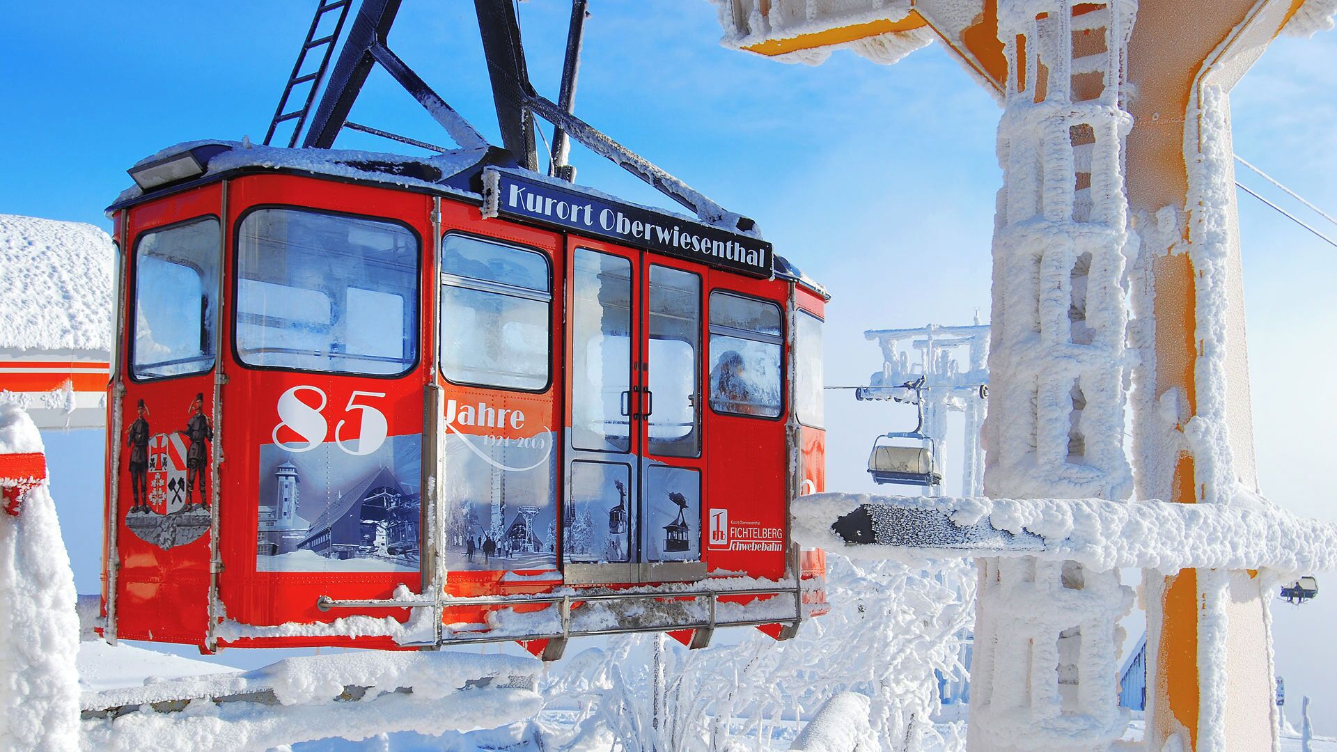 Un teleférico rojo con los números '85' y 'Jahre' a la vista, rodeado de nieve.
