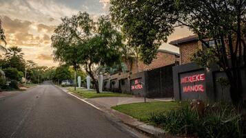 Vista de una calle con un edificio que dice 'MEREKE MANOR' y una carretera que se extiende hacia la distancia.
