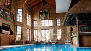 En indendørs swimmingpool med murstensvægge, store vinduer og en bindingsværkskonstruktion.