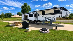 A recreational vehicle with a kitchen area, a dining table, and two chairs. - The TajMyHaul, Camper in Waterside at Blue ridge! (Morganton)