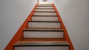 Een trap met witte treden en oranje treeplanken, die naar een deur aan de bovenkant leidt.