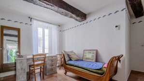 Een slaapkamer met een houten bed, een bureau met stoel, een kast en een raam met gordijnen.