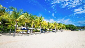 Uma praia com palmeiras, espreguiçadeiras e guarda-sóis.