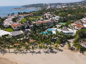 A coastal resort with multiple buildings, a swimming pool, and palm trees. - Jungle Hideaway · Private Pool & Beach Club (La Cruz de Huanacaxtle)