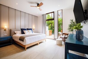 Ein modernes Schlafzimmer mit Bett, Nachttischen, Deckenventilator, Fernseher und Blick ins Freie.