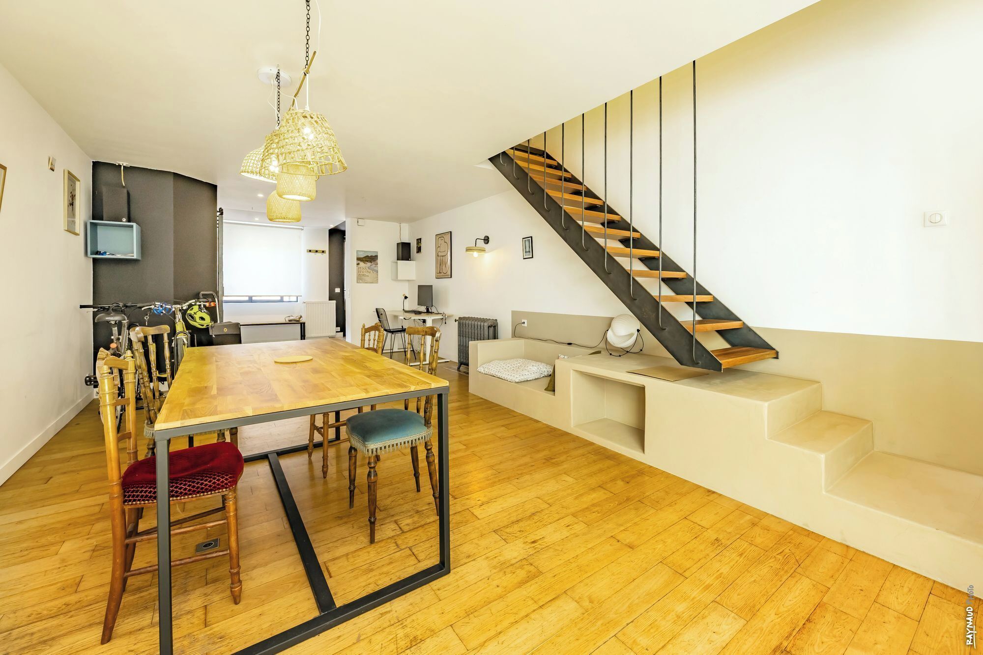 A modern interior with a dining area, kitchen, and a staircase.