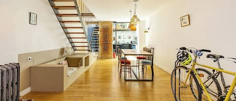 A modern interior with a wooden floor, a staircase, a dining area, and a bicycle.
