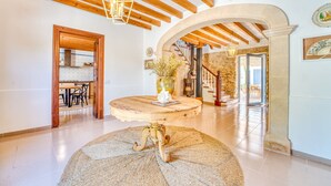 A spacious interior with a wooden ceiling, a round table with a vase, a staircase, and a stone wall. - Finca in front of the sea, Can Cuarassa, Pollensa. (Pollensa)