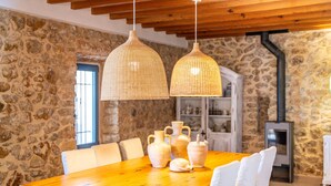 A rustic dining area with a wooden table, white chairs, and woven pendant lights. - Finca in front of the sea, Can Cuarassa, Pollensa. (Pollensa)