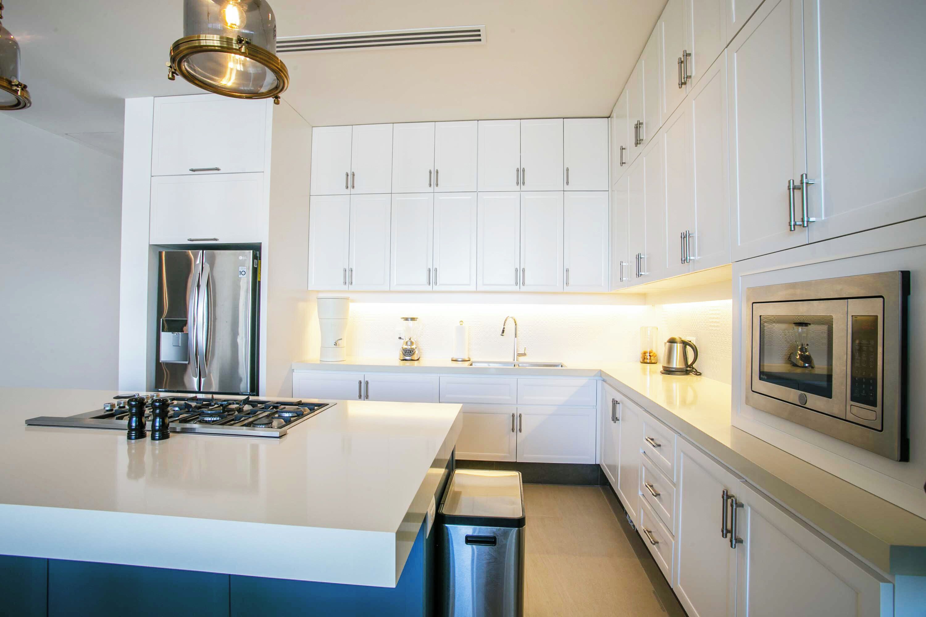 A modern kitchen with white cabinetry, stainless steel appliances, and a central island.