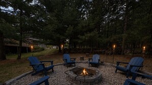 Ein Sitzbereich im Freien mit Adirondack-Stühlen und einem Feuerkorb, umgeben von Kies.