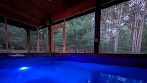 Ein Whirlpool mit Blick auf einen Wald durch große Fenster.