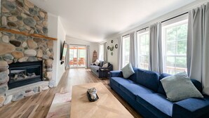 Ein Wohnzimmer mit Kamin aus Stein, einem blauen Sofa und einem Holztisch.