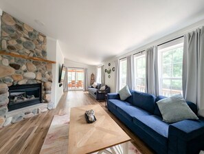 A living room with a stone fireplace, a blue sofa, and a wooden coffee table.