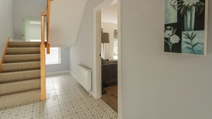 Un escalier avec des rampes en bois, un sol à motifs et un tableau accroché au mur.