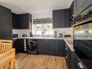 Una cucina moderna con mobili scuri, una lavatrice integrata e una finestra vista verde.