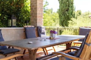 An outdoor patio with a wooden table, chairs, and a vase with flowers. - Villa Experience with Private Pool & Wine Cellar (Baderna)