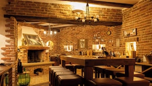 Een rustiek interieur met blootliggende bakstenen muren, een houten bar en een open haard.