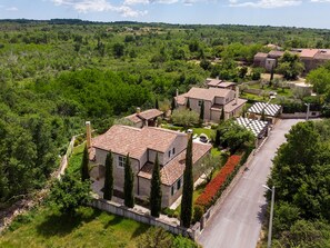 A residential area with houses featuring terracotta roofs, surrounded by greenery and a clear road. - Villa Experience with swimming pool (Baderna)