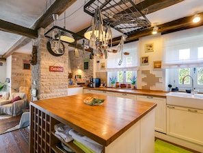 A kitchen with a wooden island, hanging utensils, and a stone wall. - Villa Experience with swimming pool (Baderna)