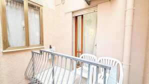 A balcony with a metal railing, two white plastic chairs, a wooden door, and a window with a wooden frame. - Cà 4 Nevodi Nonna Chiara Destro by Ca-Sa Check (Chioggia)