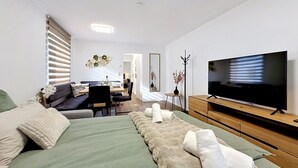 Une chambre d’hôtel moderne équipée d’un lit, d’une télévision, d’un coin repas et d’un miroir.
