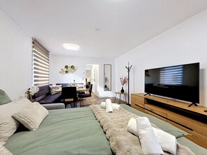 Ein modernes Hotelzimmer mit Bett, Fernseher, Essbereich und Spiegel.
