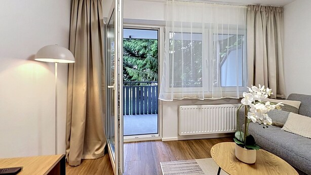 Un salon moderne comprenant un canapé, une table basse, une lampe et une porte-fenêtre coulissante donnant sur un balcon.