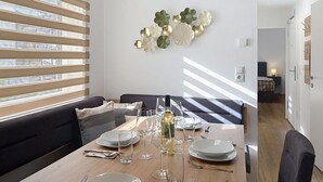 Un coin repas avec une table dressée pour quatre personnes, un canapé et un élément décoratif mural.