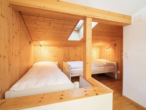 Ein gemütlicher Raum mit zwei Betten, Holzwänden, einem Oberlicht und einer weißen Decke.