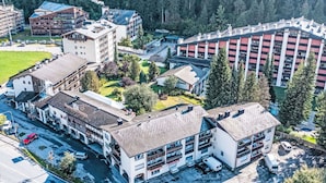Ein Luftbild eines mehrstöckigen Hotels mit einem zentralen Innenhof, umgeben von Bäumen und weiteren Gebäuden.