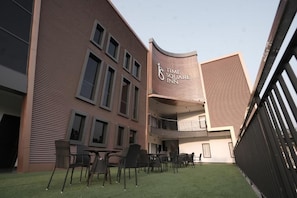 A modern building with a curved facade, a sign for 'Time Square Inn,' outdoor seating with chairs and tables, and a small grassy area.